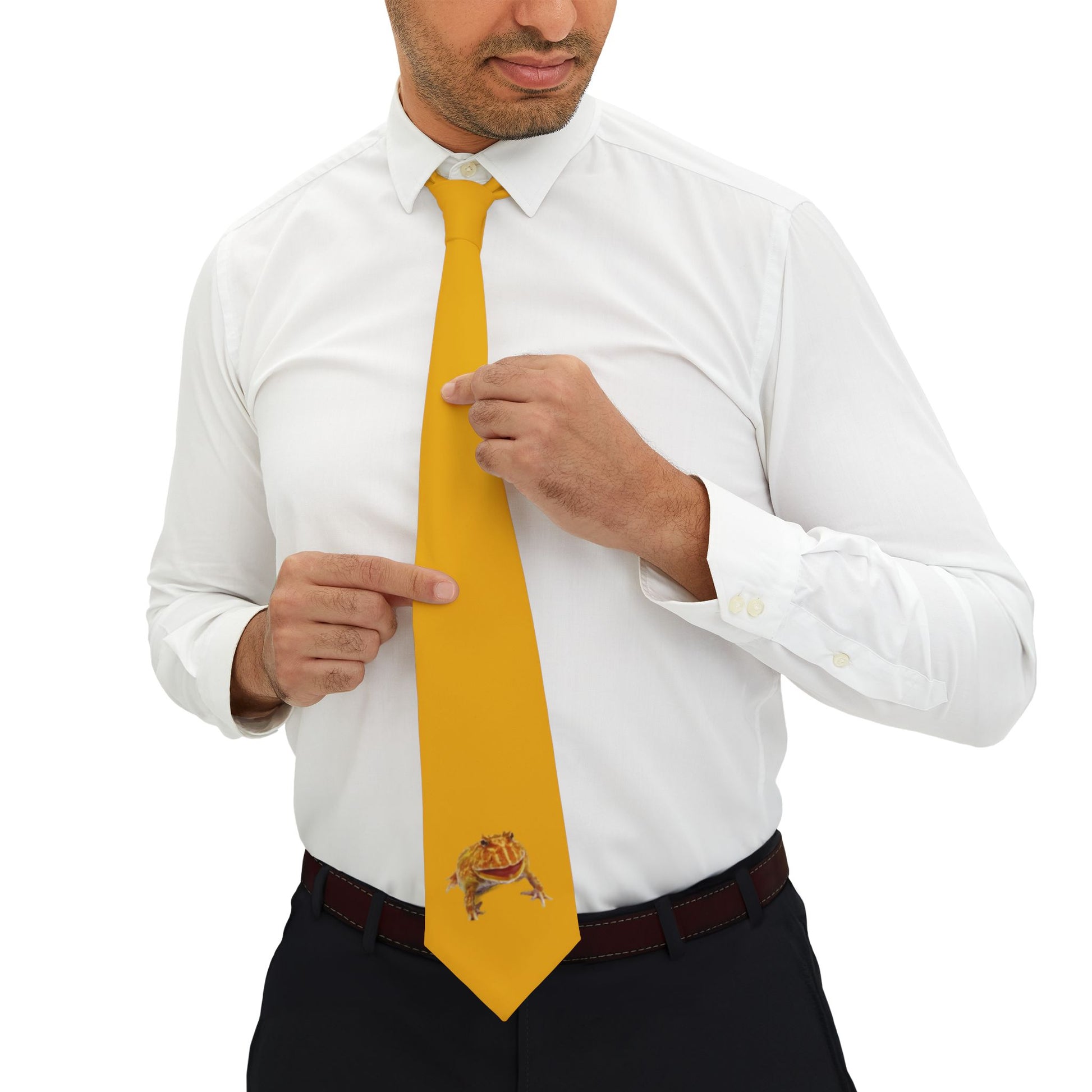 A man in a white shirt and black pants is adjusting his yellow tie, which has a frog design on it.