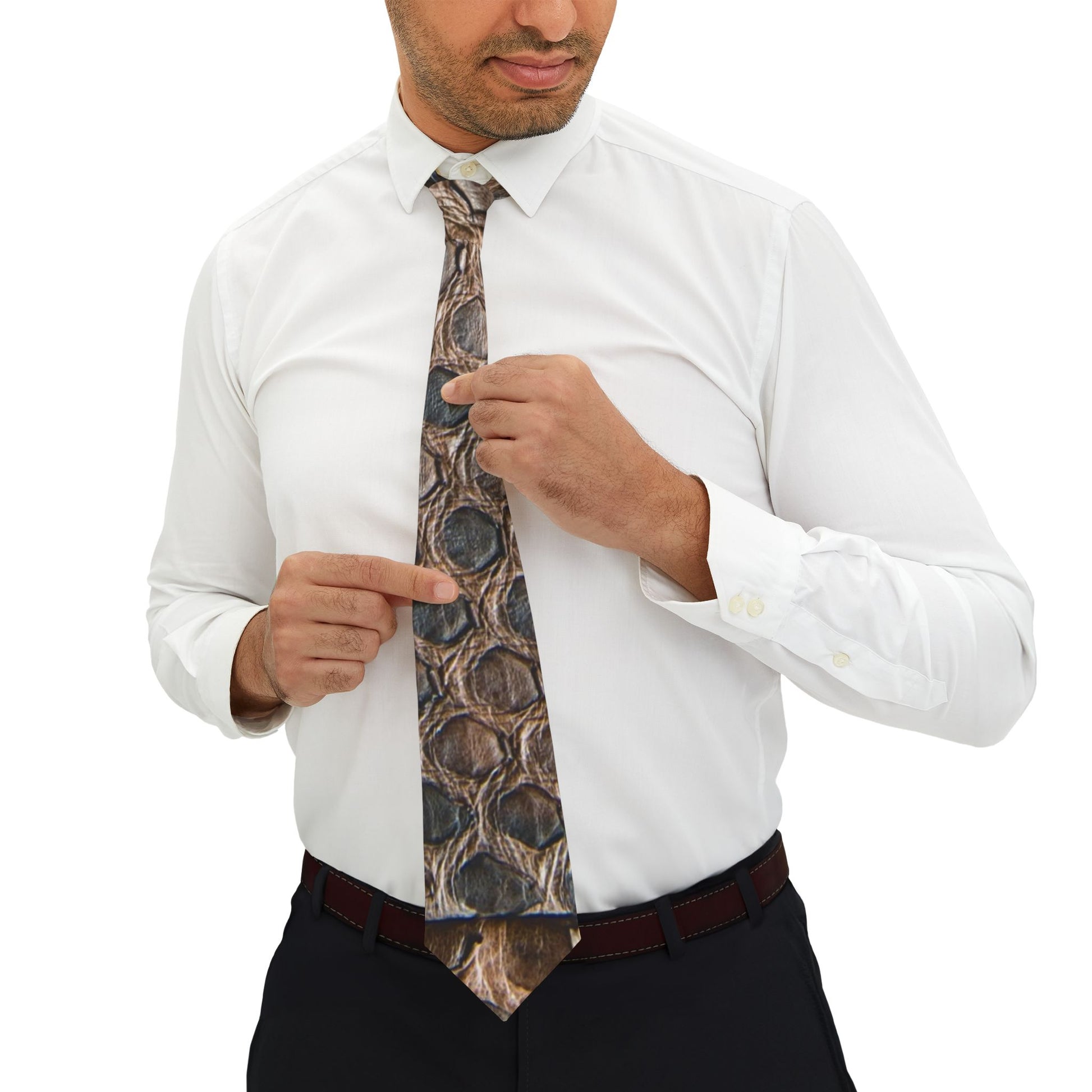 A man in a white shirt and black pants is adjusting his tie, pointing to the pattern on the tie.