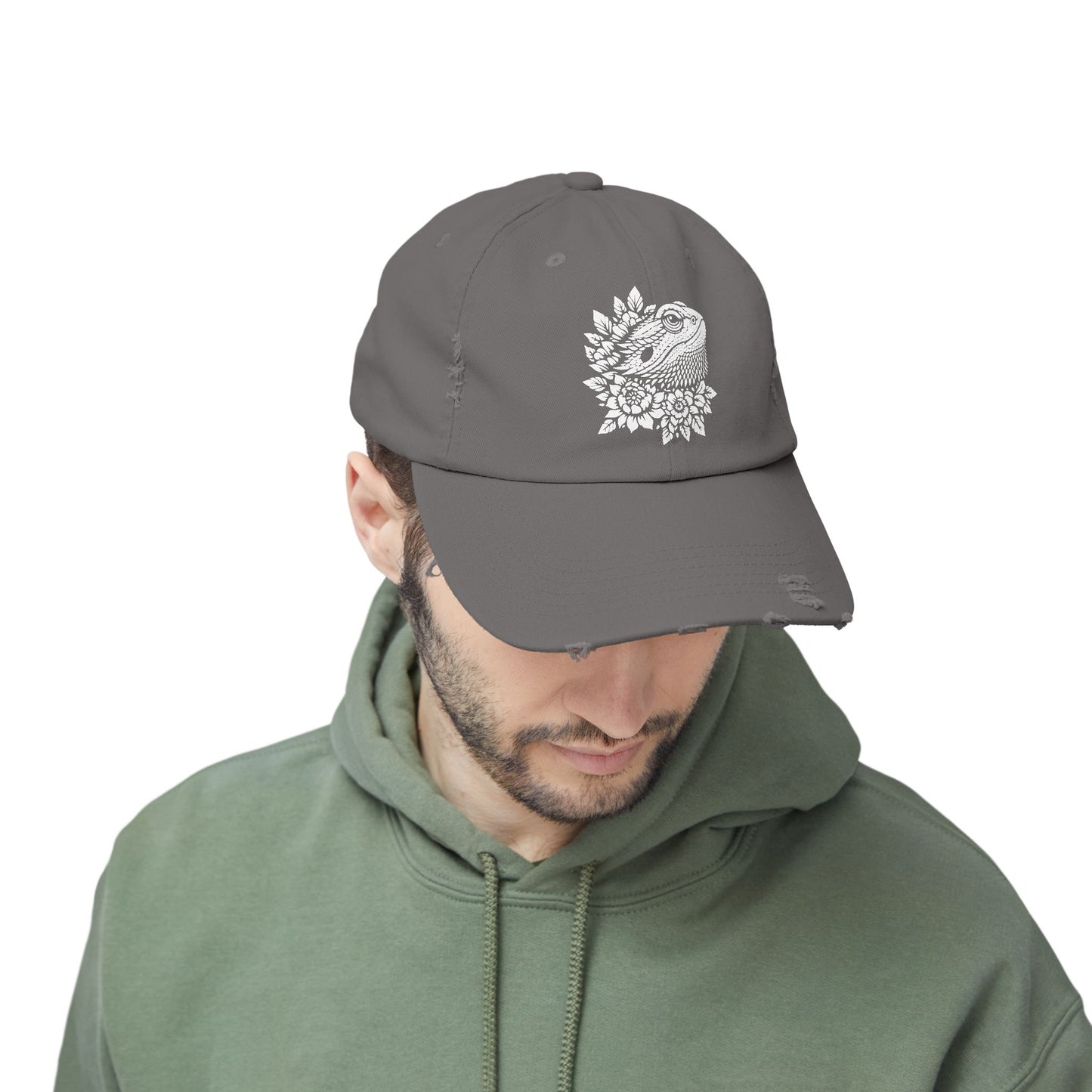 A man wearing a gray baseball cap with a white floral design on it.