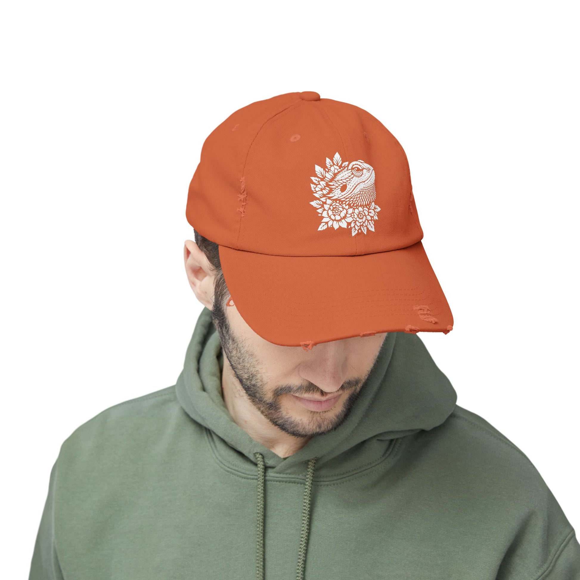 A man wearing an orange baseball cap with a white floral design on it.