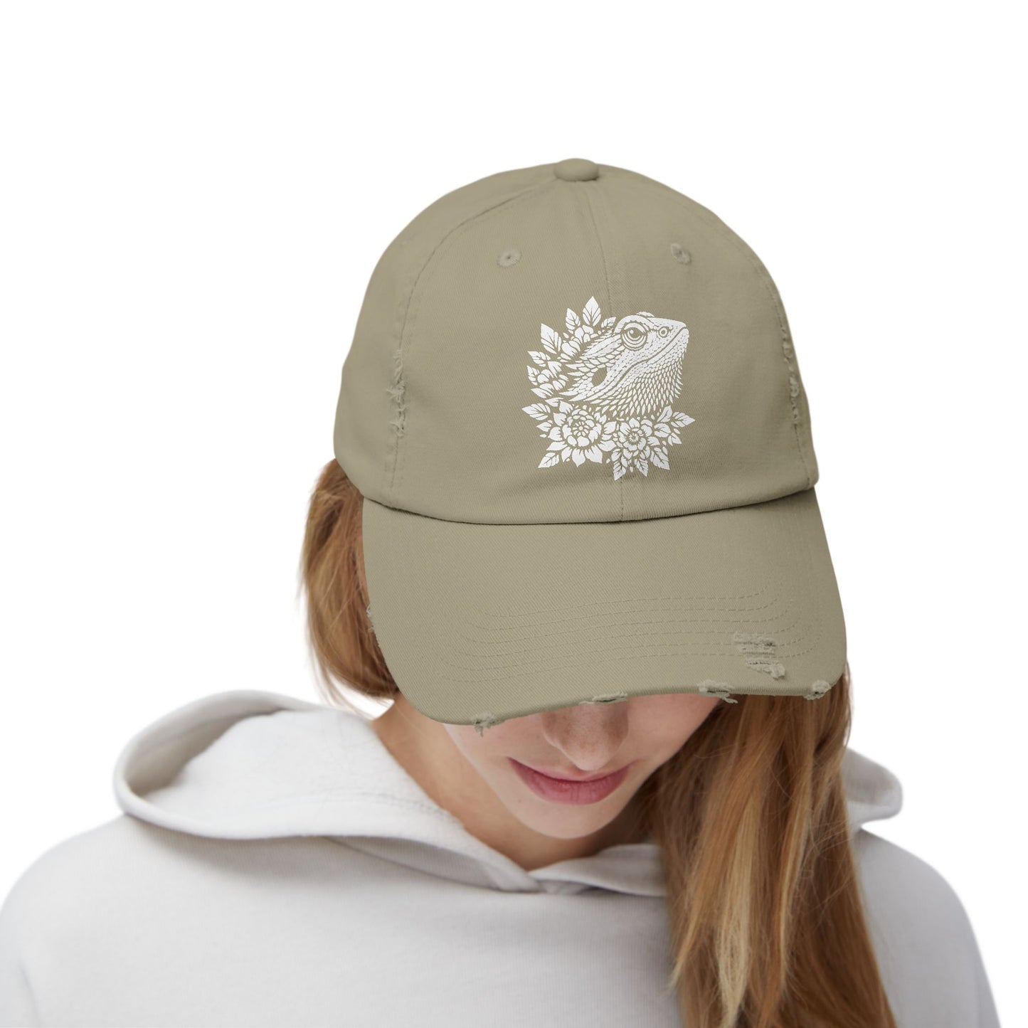 A person wearing a beige baseball cap with a white floral design on the front.