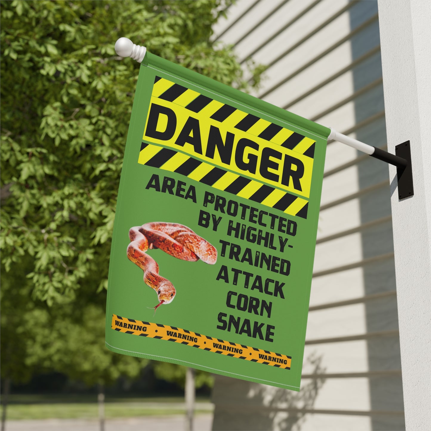 a green and yellow sign with a warning about a highly trained attack corn snake.