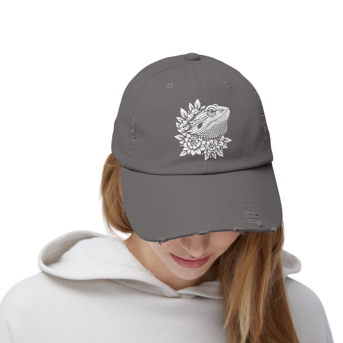 A person wearing a gray baseball cap with a white floral design on the front.