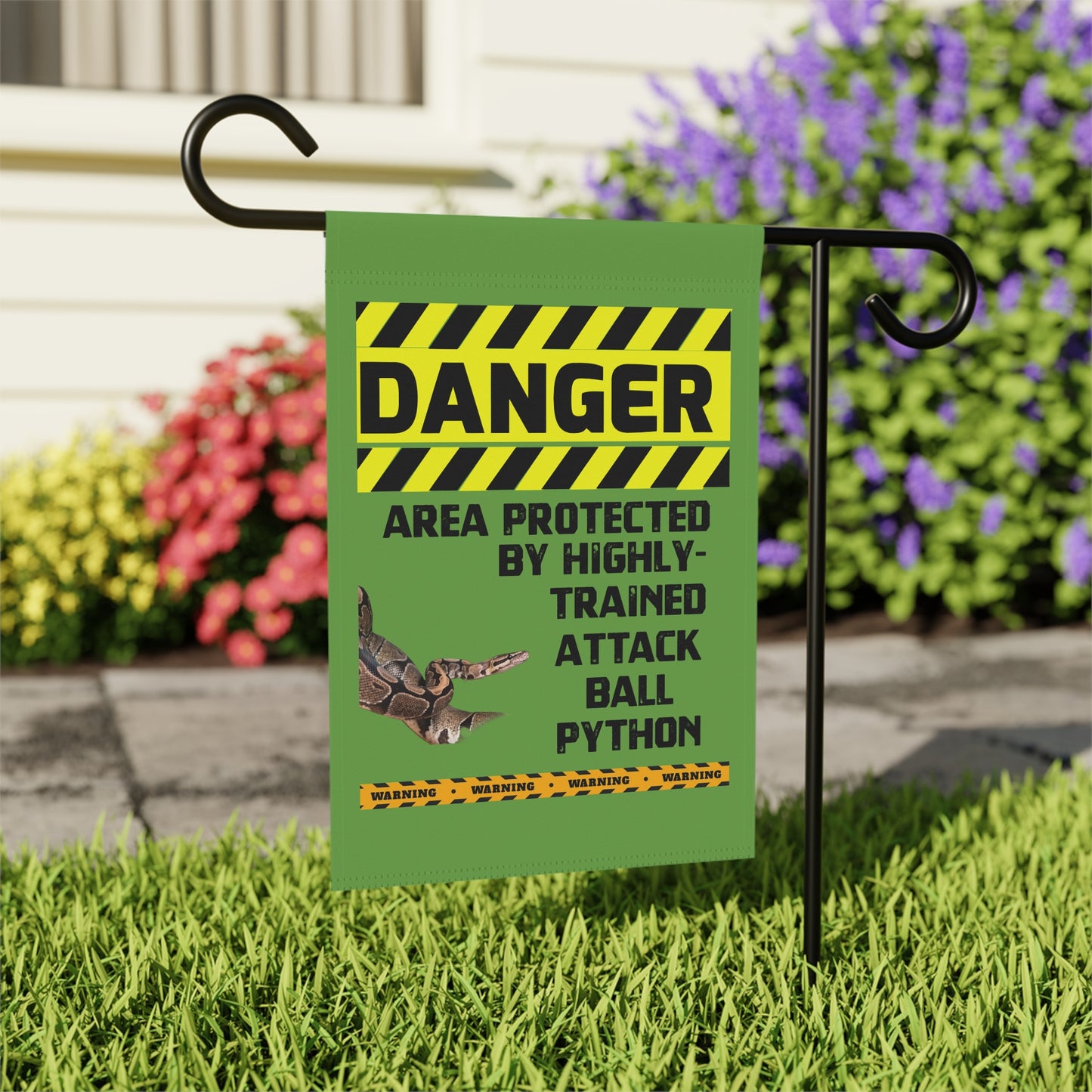 A green sign with a yellow and black striped border, warning that the area is protected by highly trained attack ball pythons.